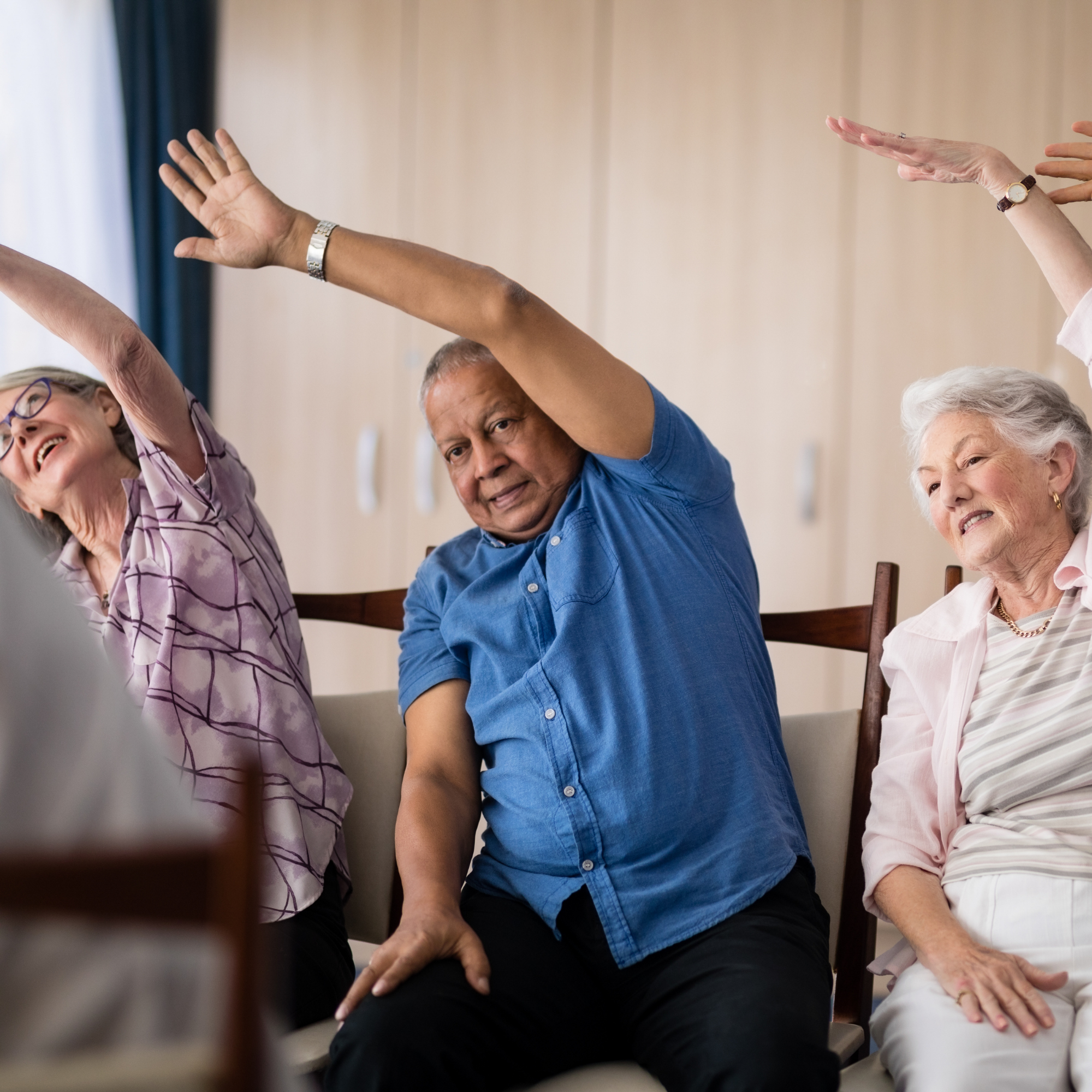 A group of older individuals completing chair exercises and stretches.