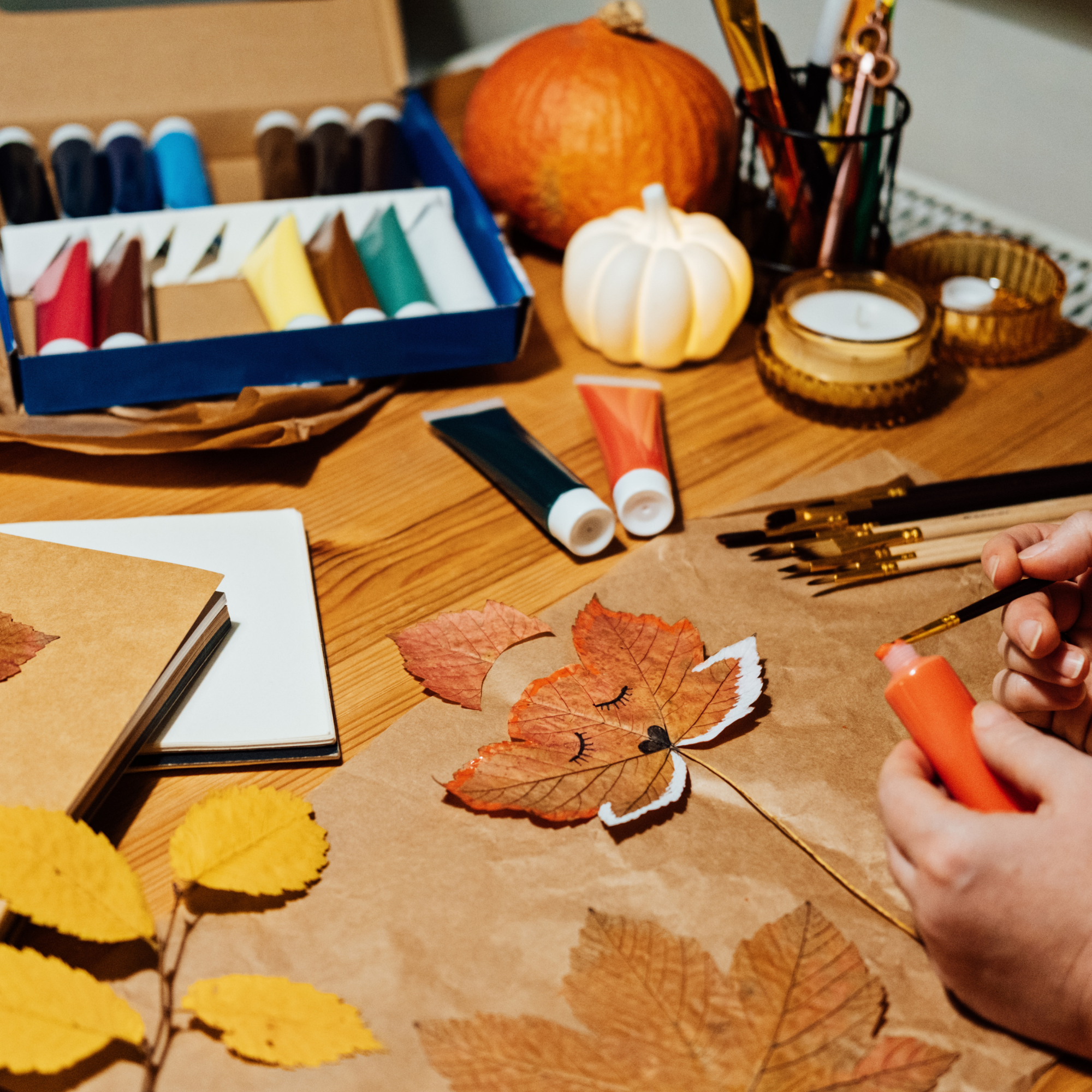 Photo showing hands painting fall themed objects such as leaves.